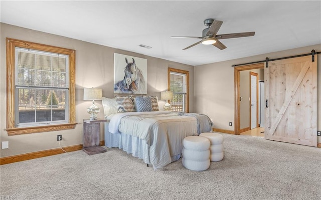 bedroom with a barn door, carpet flooring, a ceiling fan, visible vents, and baseboards