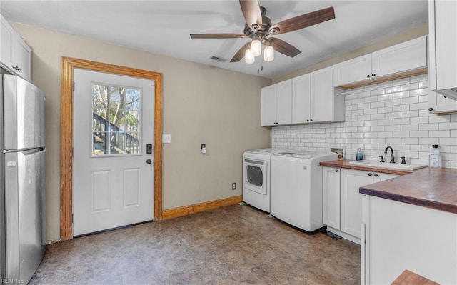 laundry area with ceiling fan, washing machine and dryer, a sink, visible vents, and baseboards