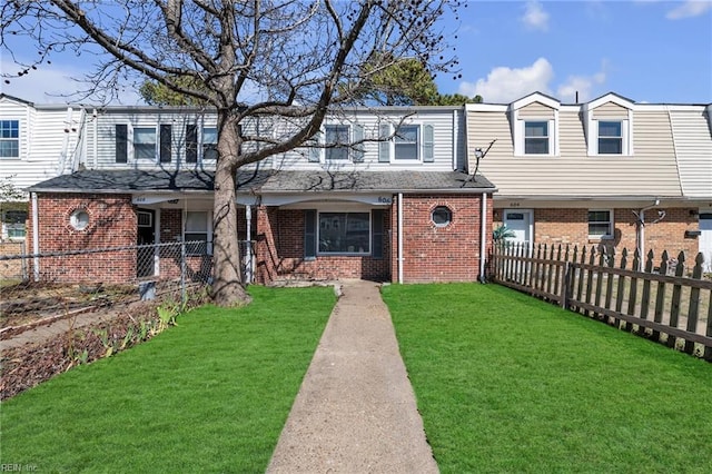 townhome / multi-family property featuring fence, a front lawn, and brick siding