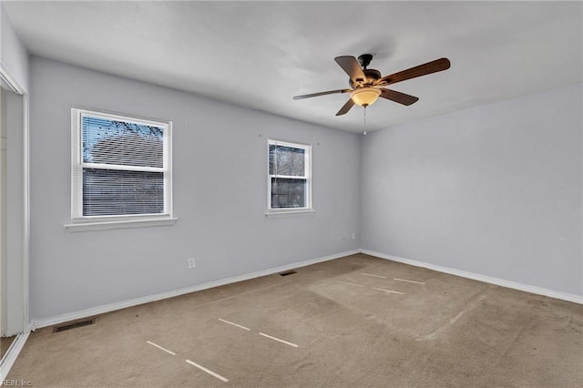 carpeted empty room featuring baseboards, visible vents, and a ceiling fan