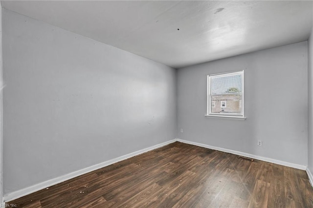 spare room featuring wood finished floors, visible vents, and baseboards