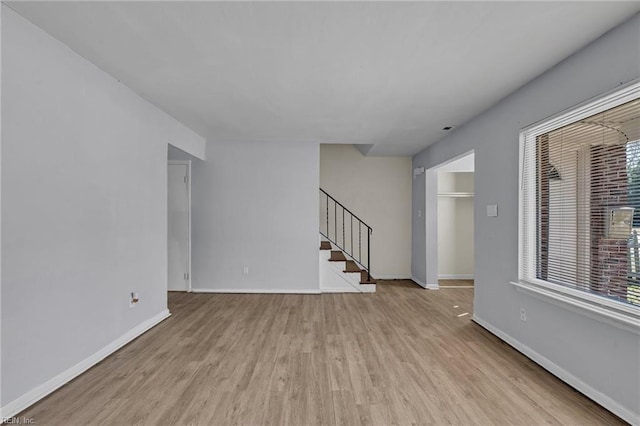 spare room featuring stairway, baseboards, and wood finished floors