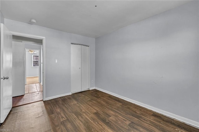 unfurnished bedroom with a closet, baseboards, and wood finished floors