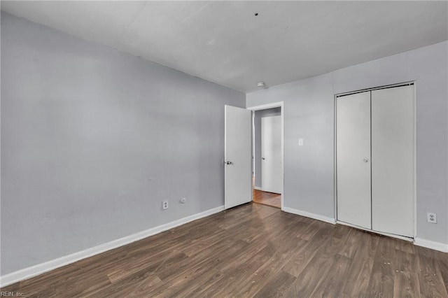 unfurnished bedroom featuring a closet, baseboards, and wood finished floors