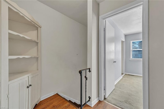 corridor featuring baseboards and wood finished floors