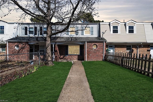 multi unit property with brick siding, a front lawn, and fence