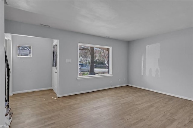 empty room featuring light wood-style floors, visible vents, and baseboards