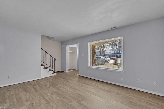 interior space with baseboards, stairs, visible vents, and wood finished floors