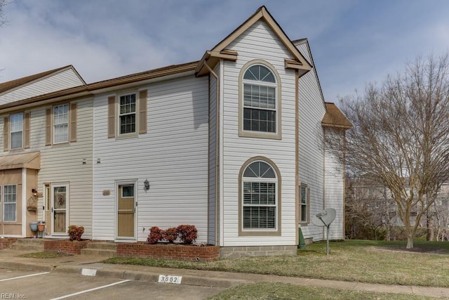 townhome / multi-family property featuring uncovered parking, entry steps, and a front lawn