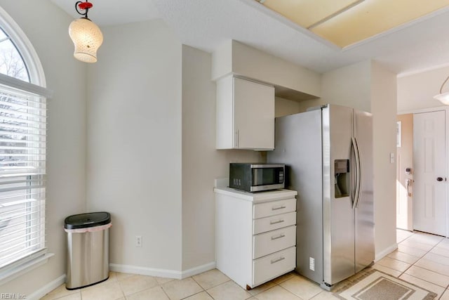 kitchen with baseboards, white cabinets, appliances with stainless steel finishes, hanging light fixtures, and light tile patterned flooring