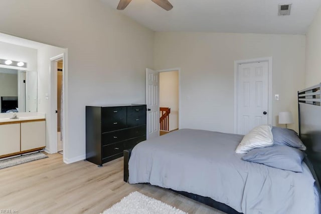 bedroom with light wood-style floors, lofted ceiling, visible vents, and ensuite bathroom