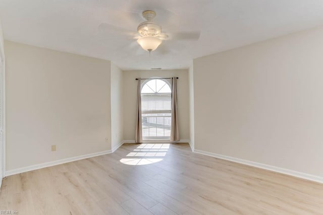 spare room with light wood-type flooring, a ceiling fan, and baseboards