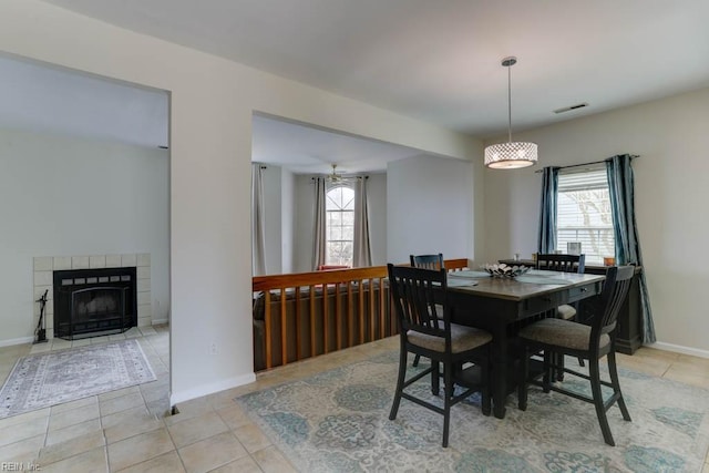 dining room with a healthy amount of sunlight, visible vents, a fireplace, and light tile patterned floors