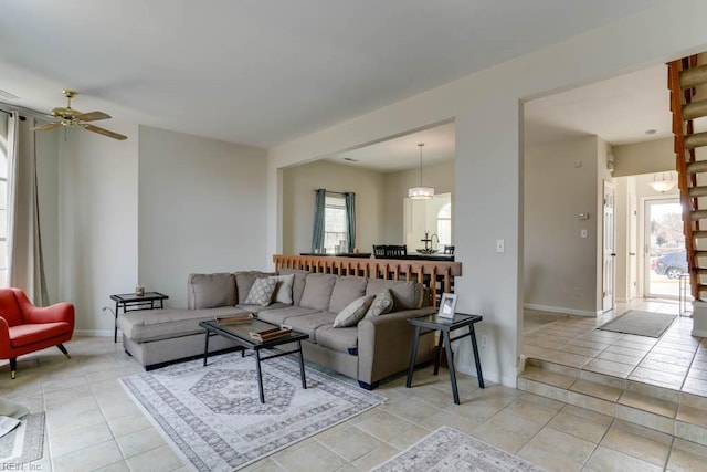 living area featuring a ceiling fan, baseboards, and light tile patterned floors