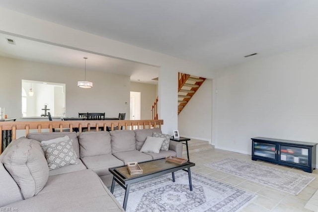 living area featuring light tile patterned floors, visible vents, and stairs