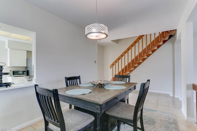 dining room with light tile patterned floors, baseboards, and stairway