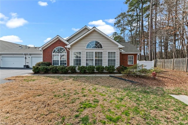 ranch-style house with brick siding, aphalt driveway, an attached garage, fence, and a front yard