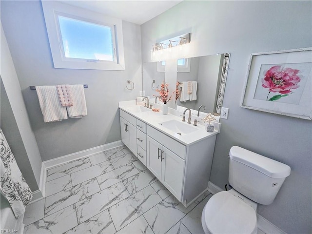 bathroom with marble finish floor, double vanity, toilet, a sink, and baseboards