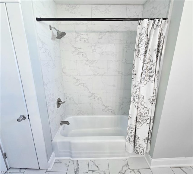 bathroom with marble finish floor, shower / bath combo with shower curtain, and baseboards