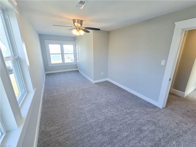 empty room featuring a ceiling fan, carpet, visible vents, and baseboards