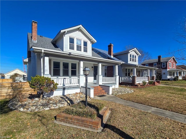 view of front facade with a chimney, a front lawn, and a porch