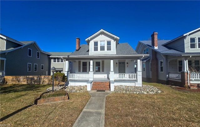 bungalow-style house with covered porch, a chimney, and a front lawn