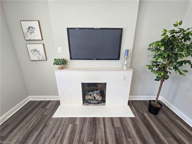 unfurnished living room featuring baseboards, dark wood finished floors, and a tiled fireplace