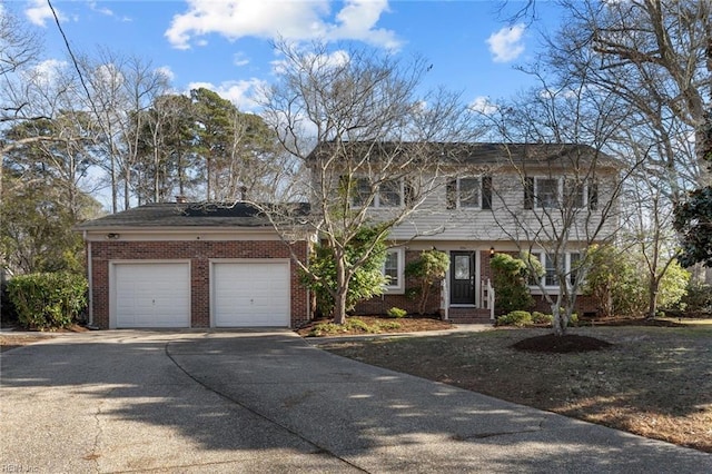 colonial inspired home with a garage, concrete driveway, and brick siding