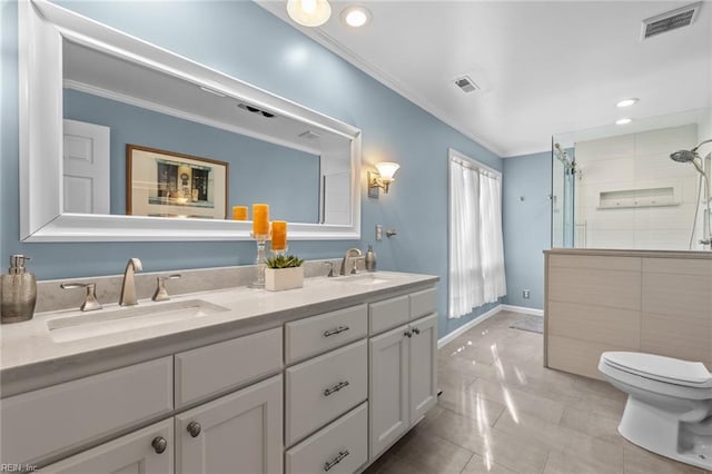 bathroom with toilet, ornamental molding, a sink, and visible vents