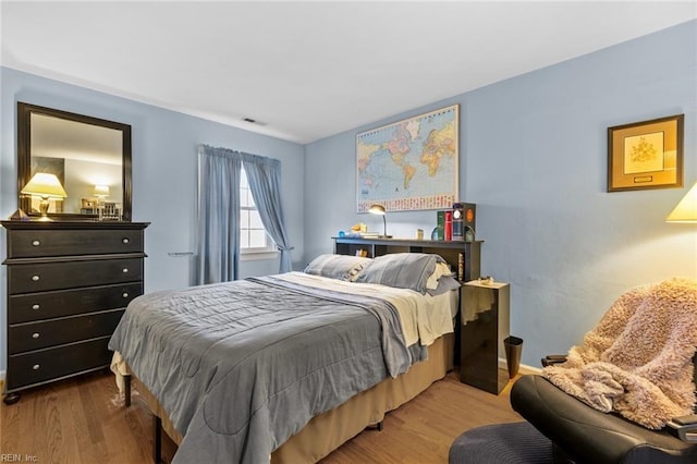 bedroom with visible vents, baseboards, and wood finished floors