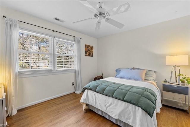 bedroom with visible vents, ceiling fan, baseboards, and wood finished floors