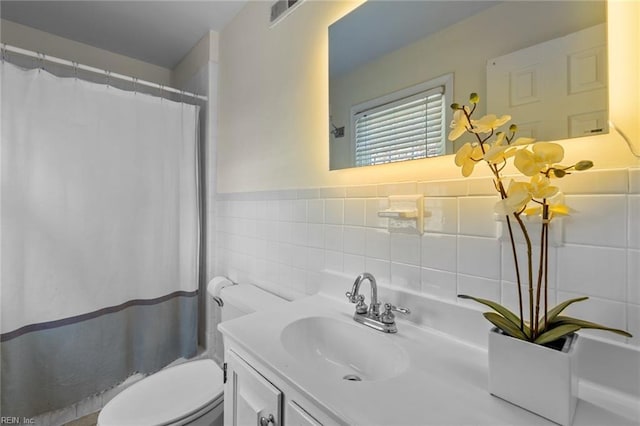 full bath featuring visible vents, toilet, curtained shower, vanity, and tile walls