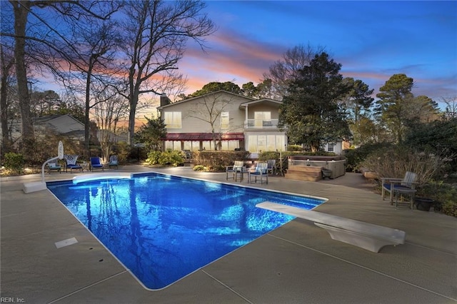 outdoor pool with a patio area and a diving board