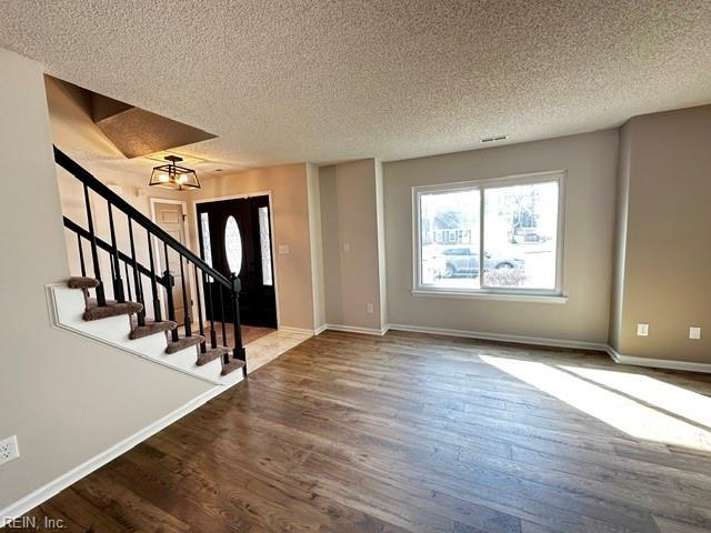 foyer entrance with stairway, wood finished floors, and baseboards