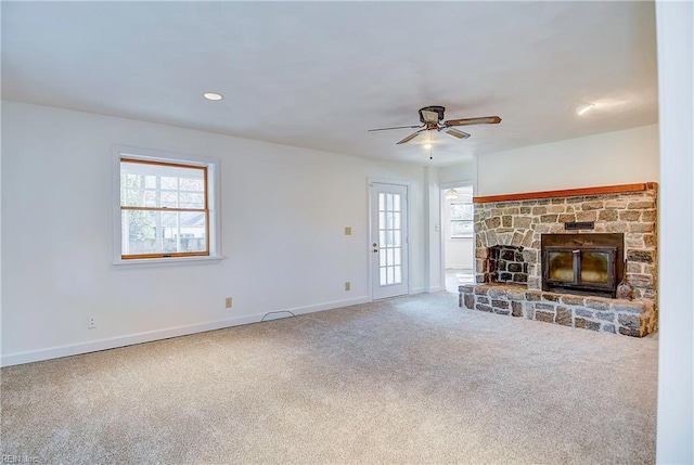 unfurnished living room with recessed lighting, carpet flooring, ceiling fan, a stone fireplace, and baseboards