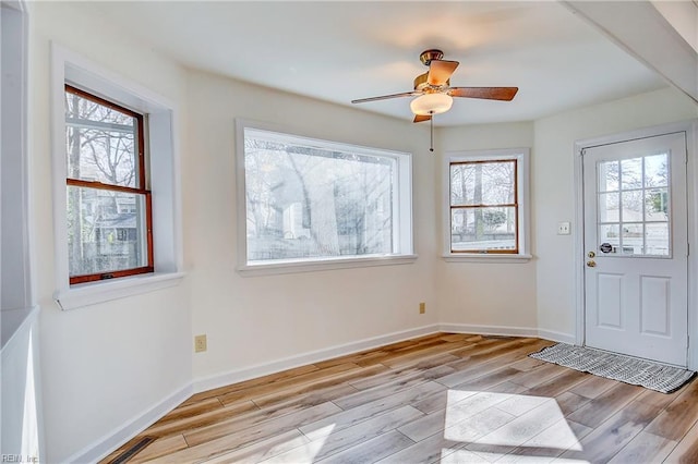 entryway with light wood finished floors, ceiling fan, and baseboards