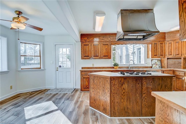 kitchen with gas stovetop, plenty of natural light, light wood finished floors, and ventilation hood