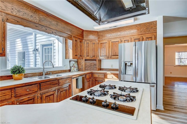 kitchen featuring white stovetop, brown cabinetry, a sink, and stainless steel fridge with ice dispenser