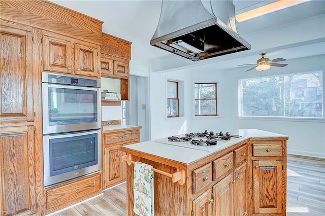 kitchen featuring range hood, a center island, white gas cooktop, light wood-style floors, and stainless steel double oven