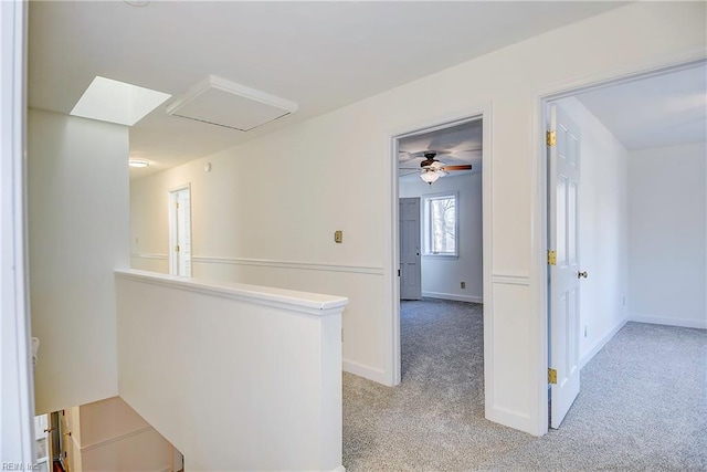 hallway featuring baseboards, an upstairs landing, and light colored carpet