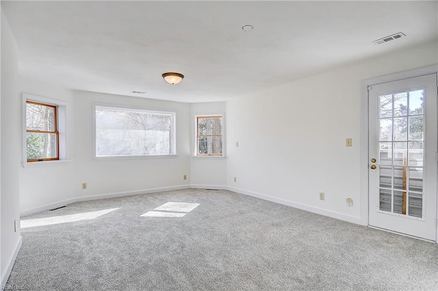 empty room featuring carpet, visible vents, and baseboards