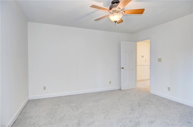 carpeted spare room featuring baseboards and a ceiling fan