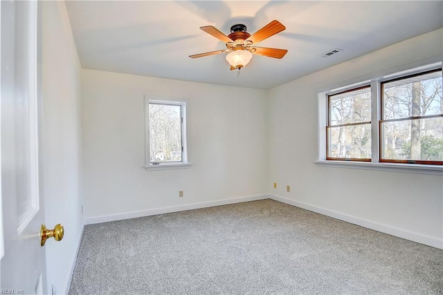 carpeted spare room featuring a ceiling fan, visible vents, and baseboards