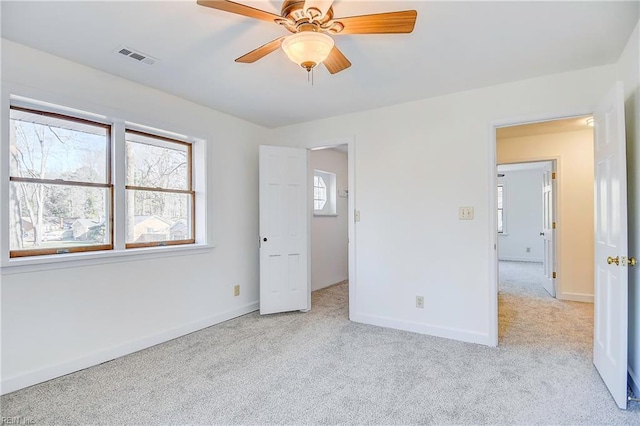 unfurnished bedroom featuring a ceiling fan, light colored carpet, visible vents, and baseboards