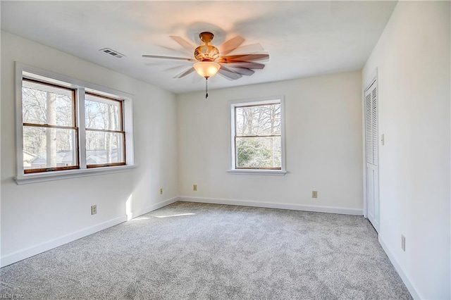 carpeted empty room featuring a ceiling fan, visible vents, and baseboards