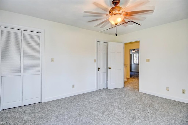 unfurnished bedroom with baseboards, multiple closets, a ceiling fan, and light colored carpet