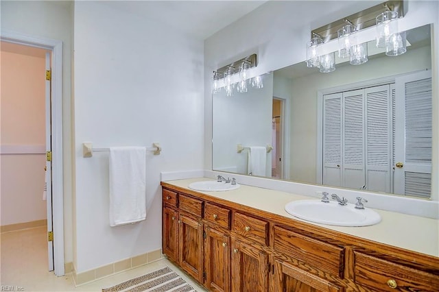 full bath featuring double vanity, tile patterned flooring, a sink, and baseboards