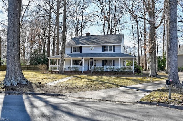 farmhouse-style home featuring driveway, covered porch, a chimney, and fence