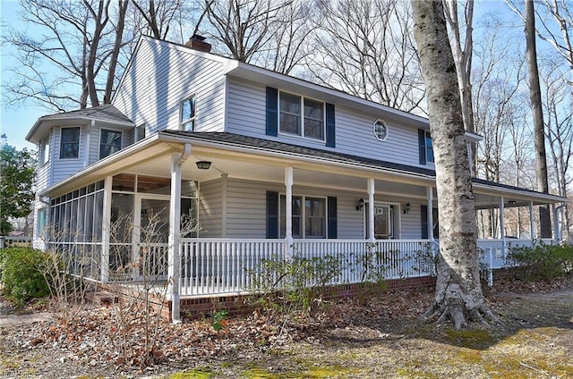 view of front facade featuring a porch, a chimney, and a sunroom