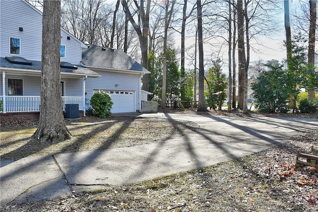 view of side of home with driveway, a shingled roof, a porch, and cooling unit